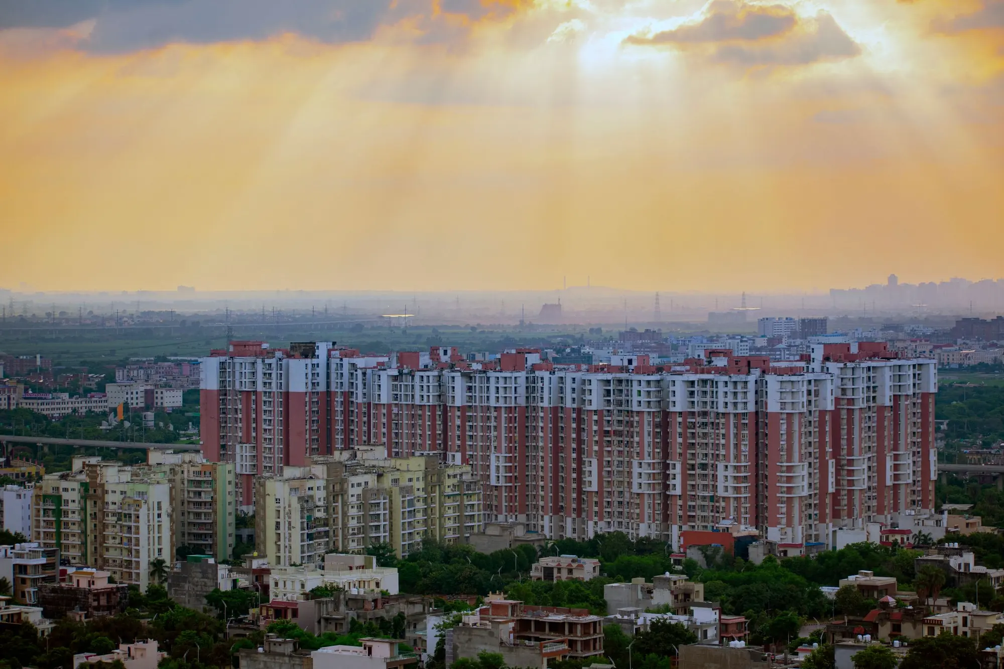 Apartment towers and low-rise homes under a sunrise sky