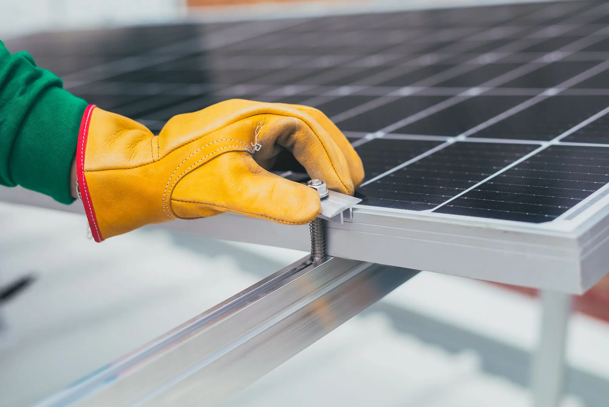 A gloved hand tightening the clamp that holds a panel to its rail