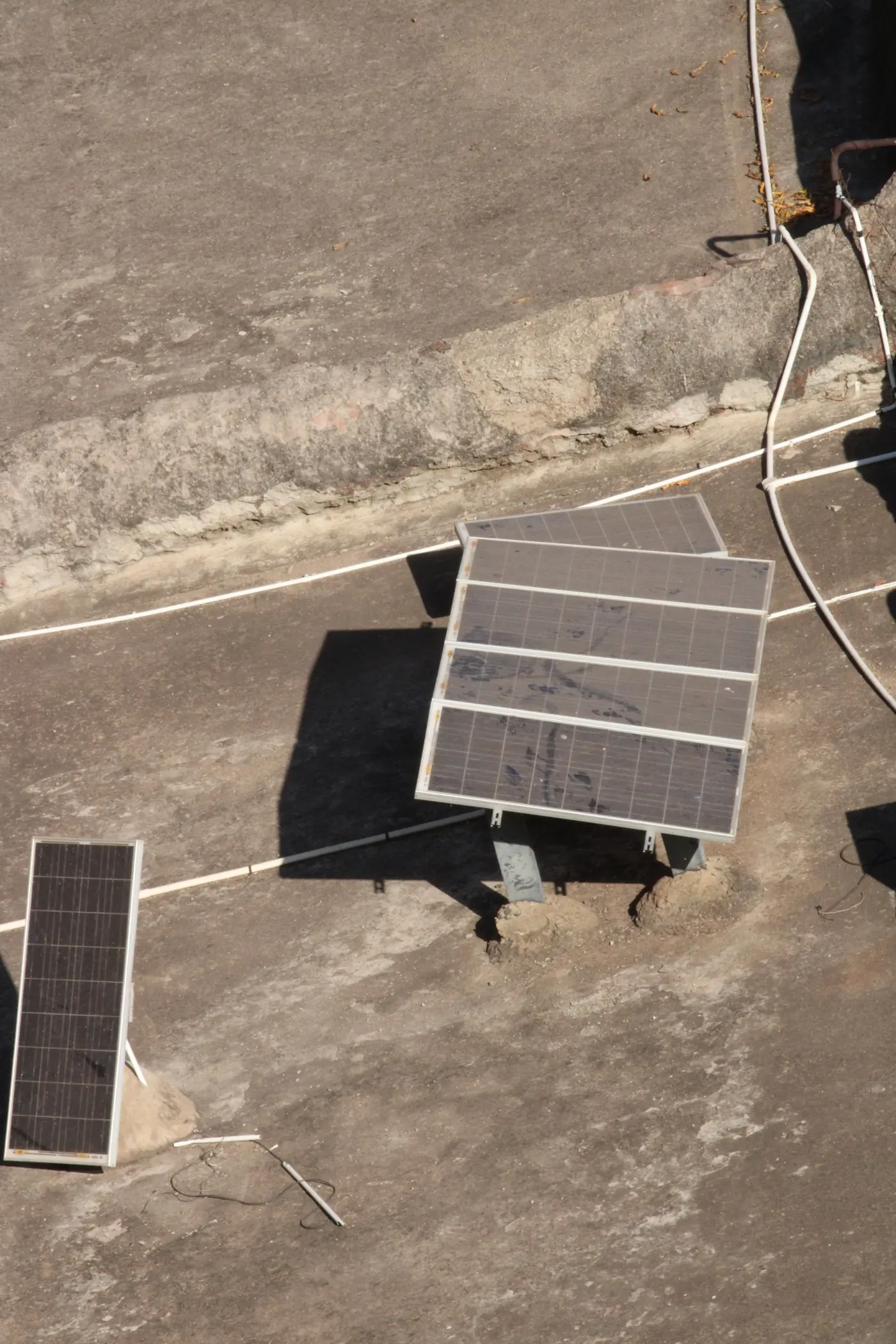 Two small solar panels on a concrete roof, seen from above